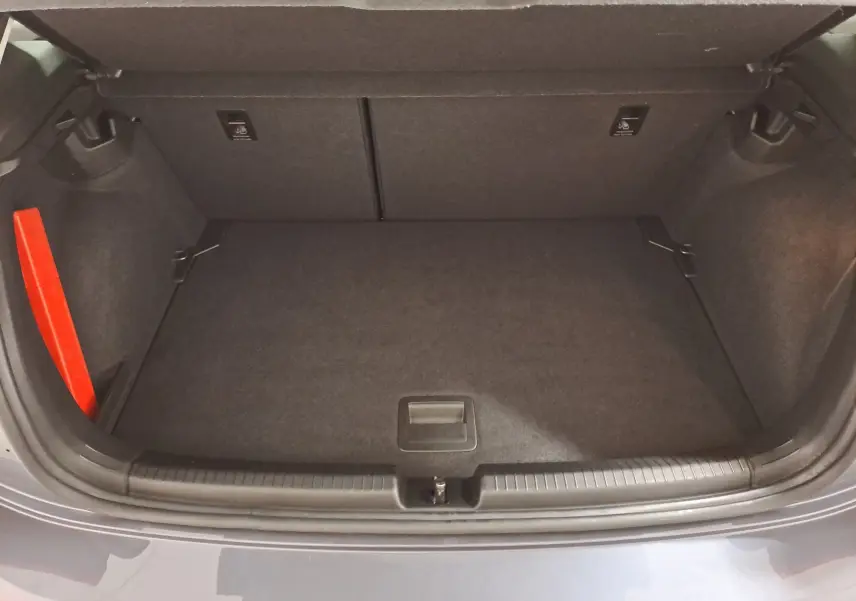 Coffre ouvert vu de l'arrière d'une Volkswagen Polo gris cendre 2025, avec intérieur de coffre propre et rangement plat.