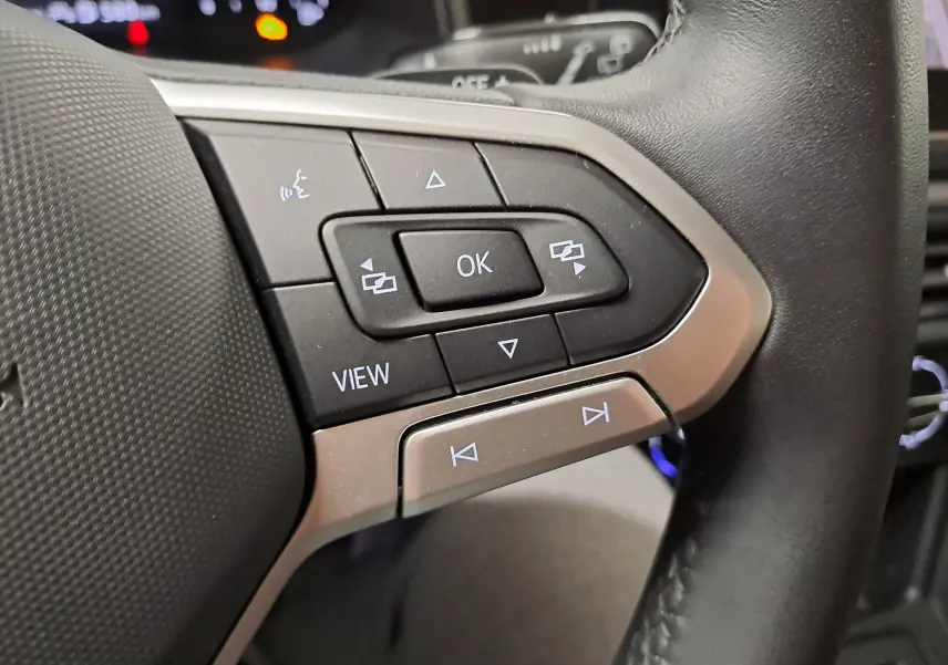 Gros plan sur les commandes multifonctions à droite du volant noir de la Volkswagen Polo gris cendre 2025.