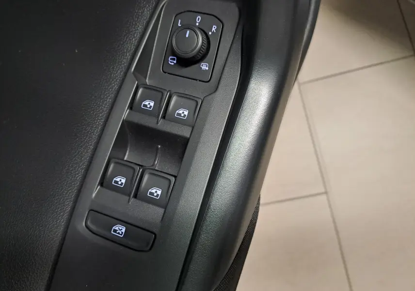 Gros plan sur les commandes de lève-vitres et rétroviseurs côté conducteur du Volkswagen Polo gris cendre 2025.