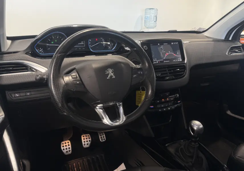 Intérieur du Peugeot 2008 2018 essence blanc, vue du poste de conduite avec volant, tableau de bord et levier de vitesses manuel.