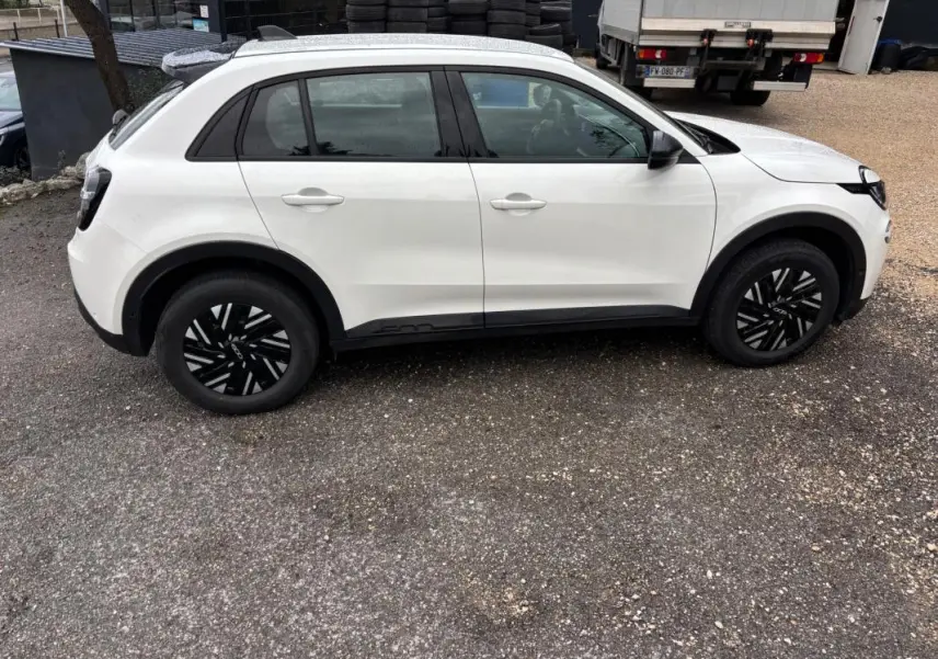 Vue de profil côté gauche d'une FIAT 600 blanche 2024 avec jantes noires et détails noirs sur les bas de caisse.