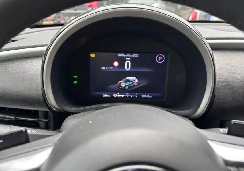 Vue rapprochée du tableau de bord numérique de la Fiat 600 blanche, affichant la vitesse à 0 km/h et l'état hybride.