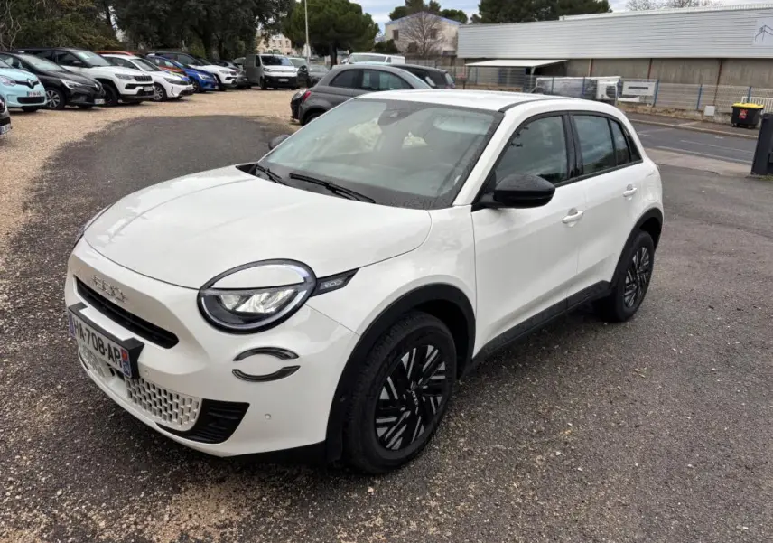 Vue 3/4 avant droite d'une FIAT 600 blanche 2024 avec jantes noires et détails noirs autour des phares.