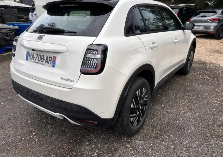 Vue 3/4 arrière droite d'une FIAT 600 blanche 2024 avec feux arrière LED et jantes noires classiques.