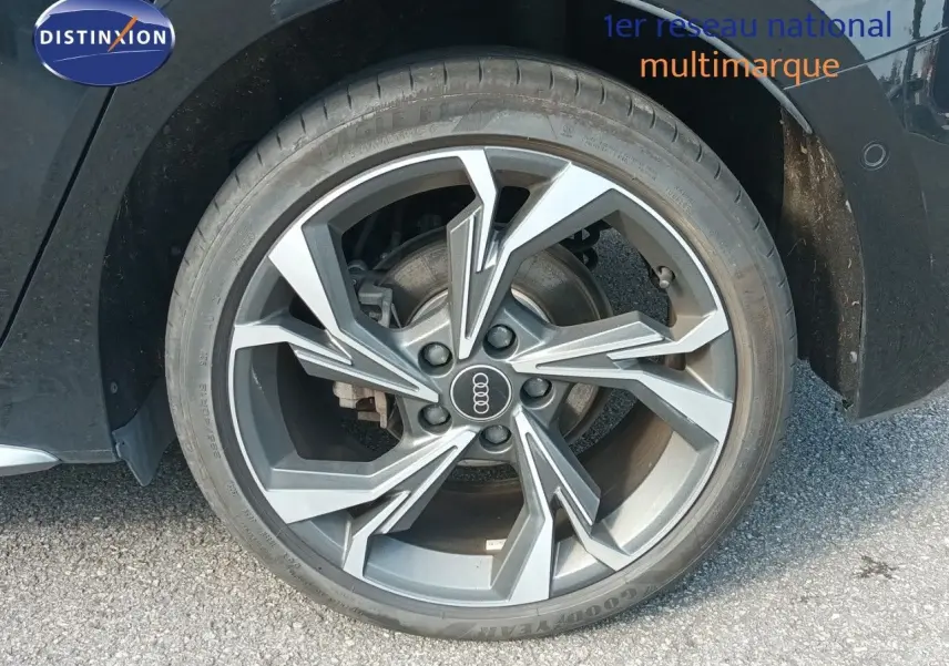 Gros plan sur la roue avant droite de l'Audi A3 Sportback noire, mettant en valeur la jante alliage au design moderne.
