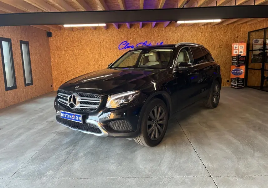 Mercedes GLC 220D Fascination noir en 3/4 avant droit, intérieur cuir beige visible, dans un garage avec murs en bois.