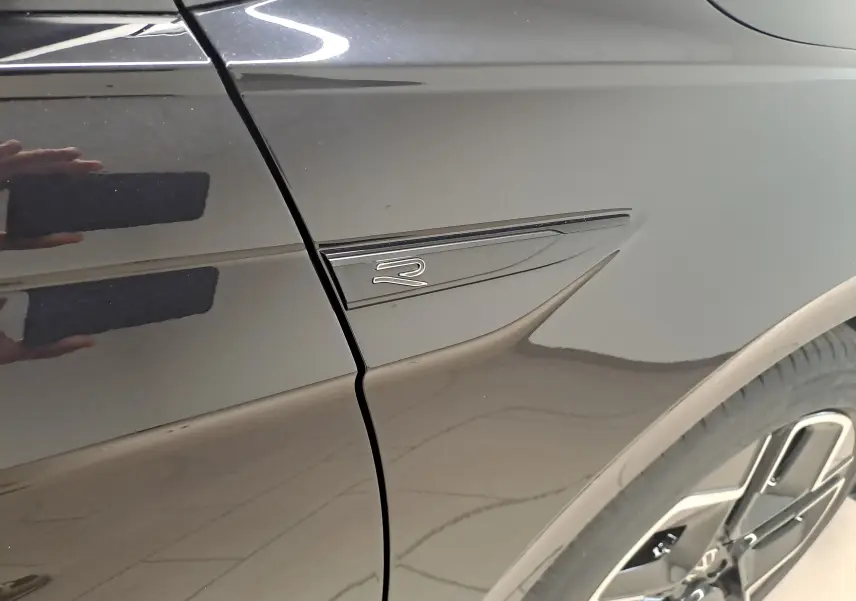 Détail de l'aile avant droite noire intense métallisée d'une Volkswagen Polo 2025 avec logo R-Line et partie de la roue.