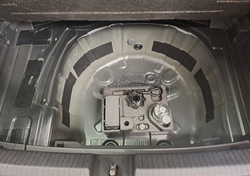 Coffre ouvert de Volkswagen Polo 2025 noir intense, vue plongeante sur le rangement sous plancher sans roue de secours.