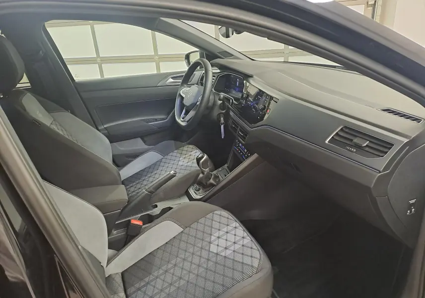Vue intérieure côté conducteur de la Volkswagen Polo 2025 noir intense, avec sièges tissu à motifs et tableau de bord moderne.
