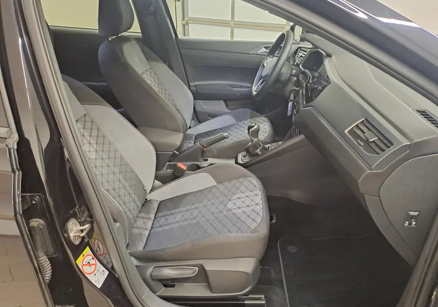 Vue intérieure côté conducteur de la Volkswagen Polo 2025 noir intense, sièges tissu à motifs et tableau de bord moderne.
