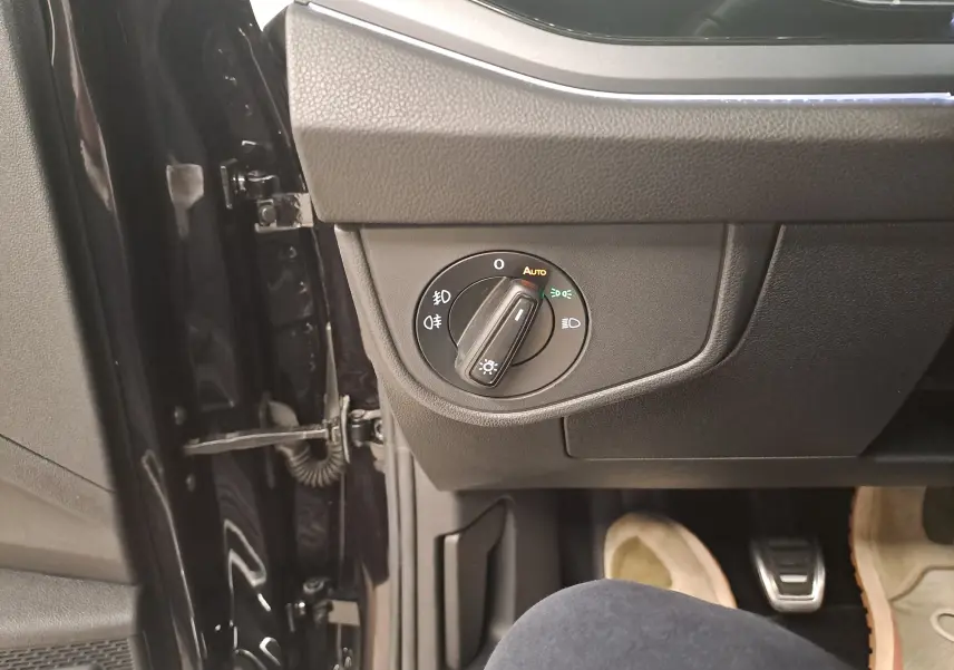 Gros plan sur le bouton de commande des phares côté gauche intérieur d'une Volkswagen Polo Noir Intense 2025.