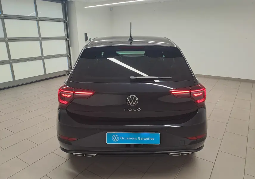 Vue arrière d'une Volkswagen Polo Noir Intense 2025 avec feux allumés et logo R-Line visible en intérieur showroom.