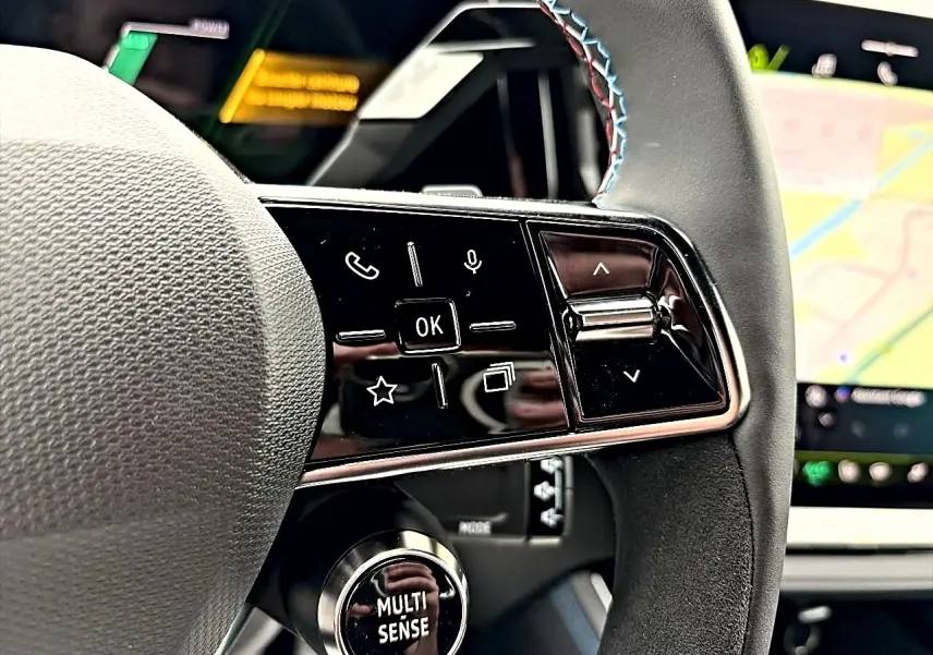 Gros plan sur le côté droit du volant du Renault Austral gris schiste, avec commandes multifonctions et écran tactile en arrière-plan.