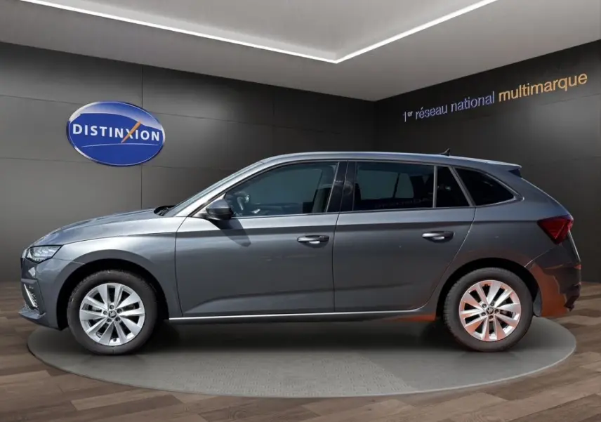 Vue latérale droite d'une Skoda Scala gris foncé en showroom avec jantes alliage et vitres teintées.