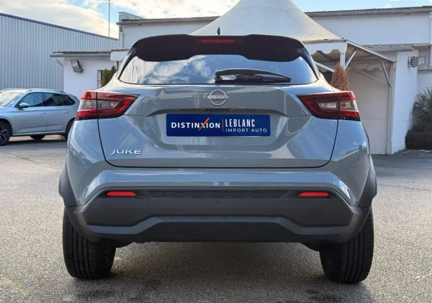 Vue arrière d'un Nissan Juke gris clair 2023 avec feux LED et spoiler de toit visible en extérieur.