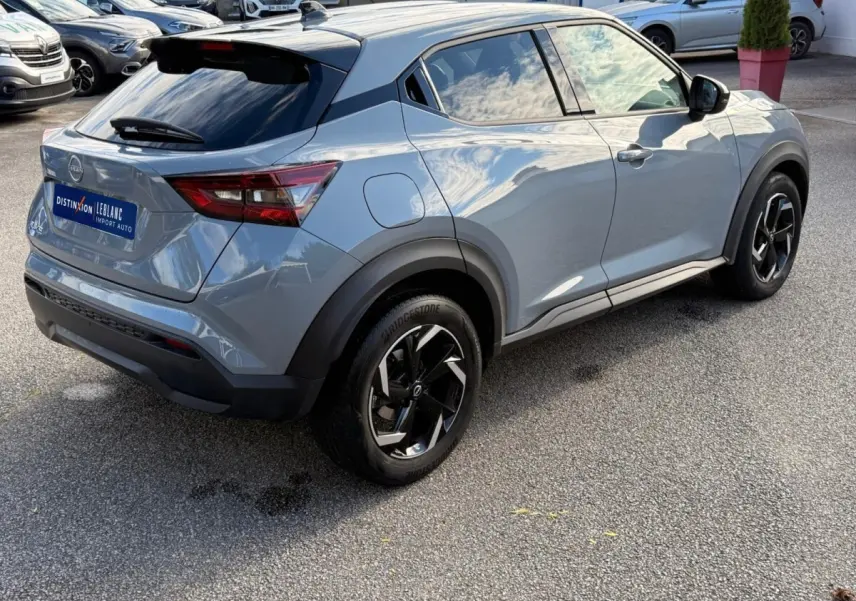 Nissan Juke gris clair vu en 3/4 arrière droit, avec jantes noires et détails noirs contrastants.