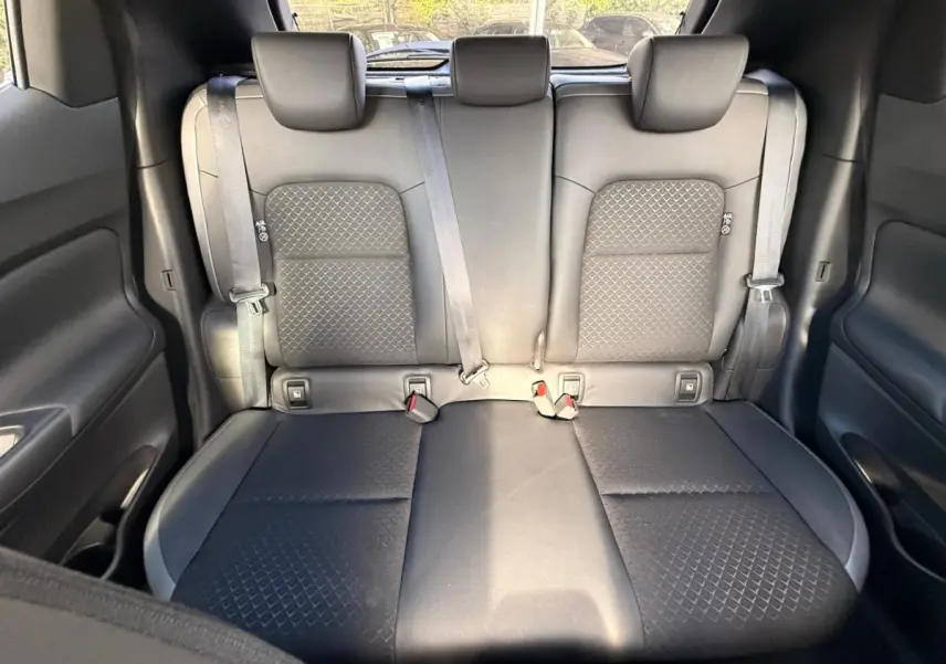 Vue intérieure sur la banquette arrière noire du Nissan Juke 2023, avec ceintures de sécurité et appuie-têtes visibles.