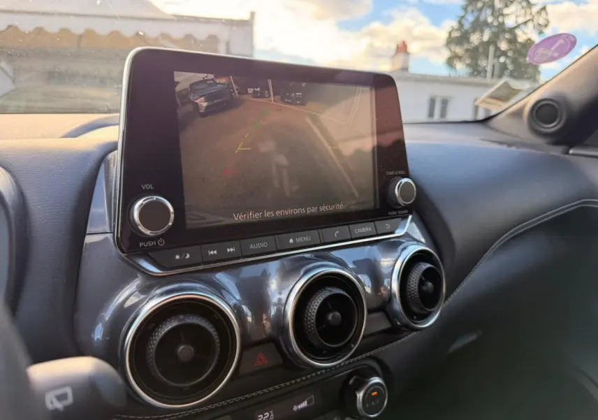 Vue intérieure du tableau de bord du Nissan Juke gris clair 2023, avec écran tactile affichant la caméra de recul.