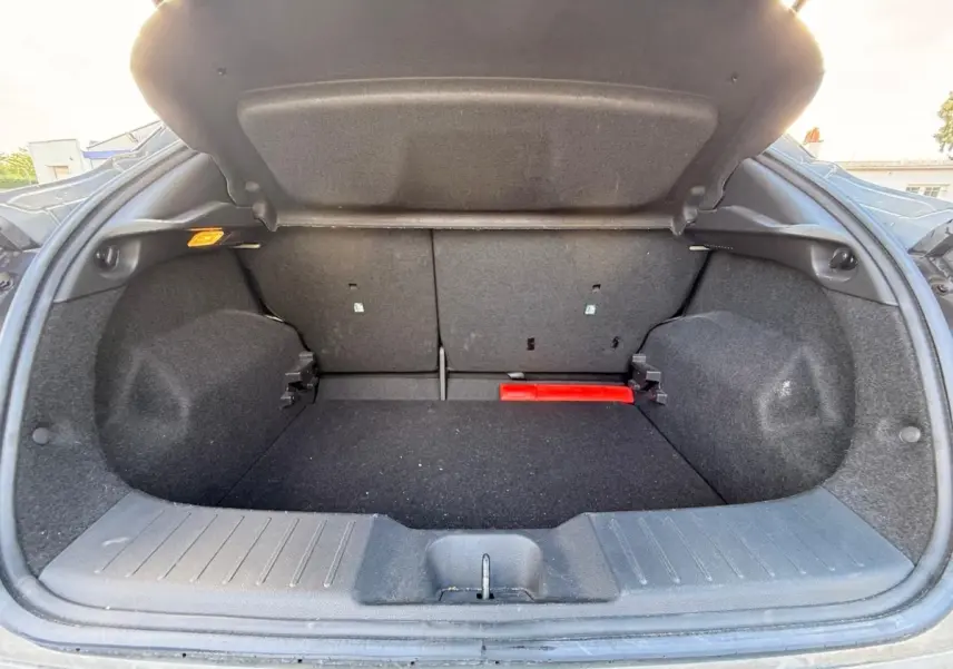 Coffre ouvert de Nissan Juke gris clair 2023, vue de l’arrière montrant l’espace de chargement et la banquette rabattable.