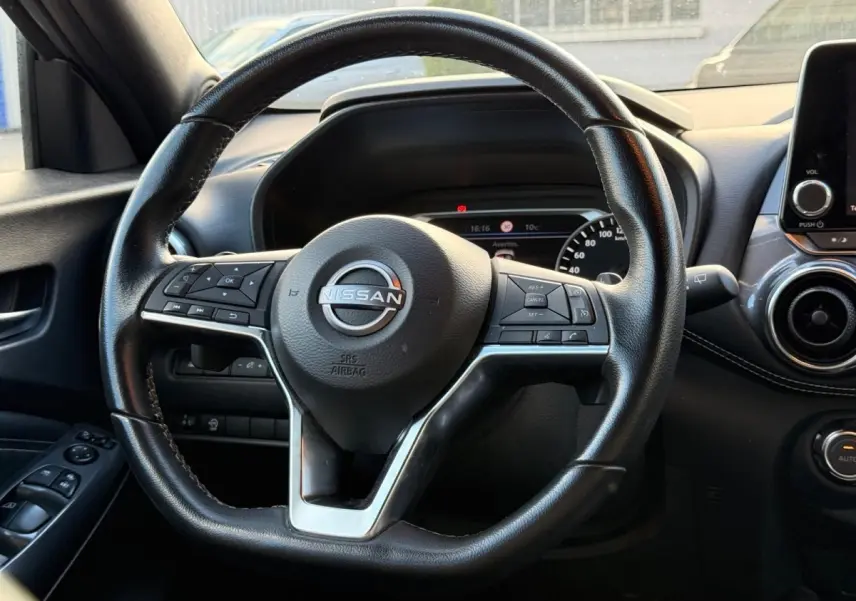 Vue rapprochée du volant cuir noir du Nissan Juke 2023 avec commandes multifonctions et tableau de bord digital.