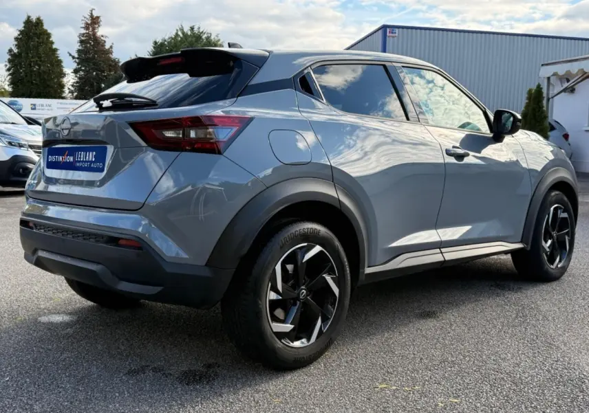 Vue 3/4 arrière droite du Nissan Juke gris clair 2023 avec jantes noires et vitres teintées.