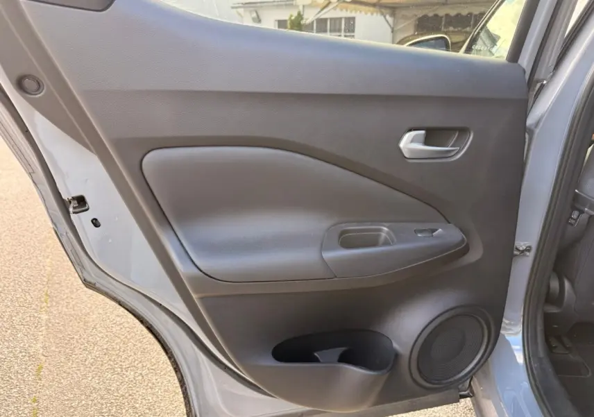 Vue rapprochée de la porte arrière gauche gris clair du Nissan Juke 2023 avec poignée et haut-parleur intégrés.