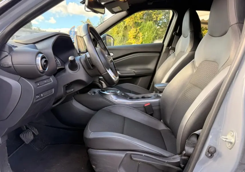 Vue intérieure côté conducteur du Nissan Juke gris clair 2023, mettant en valeur les sièges et le tableau de bord.