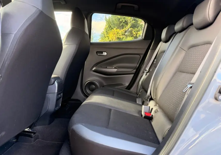 Vue intérieure côté droit sur la banquette arrière noire du Nissan Juke gris clair 2023, avec ceinture de sécurité visible.