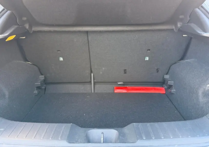 Coffre ouvert du Nissan Juke gris clair 2023, vue intérieure montrant un espace de rangement avec un triangle de signalisation rouge.