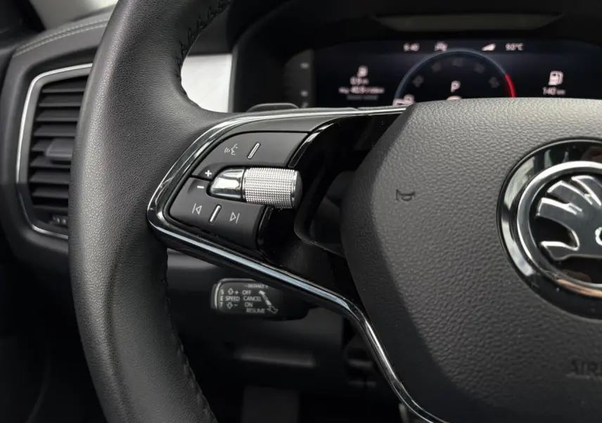 Gros plan sur le volant noir du Skoda Kodiaq 2024 avec commandes intégrées et tableau de bord digital en arrière-plan.