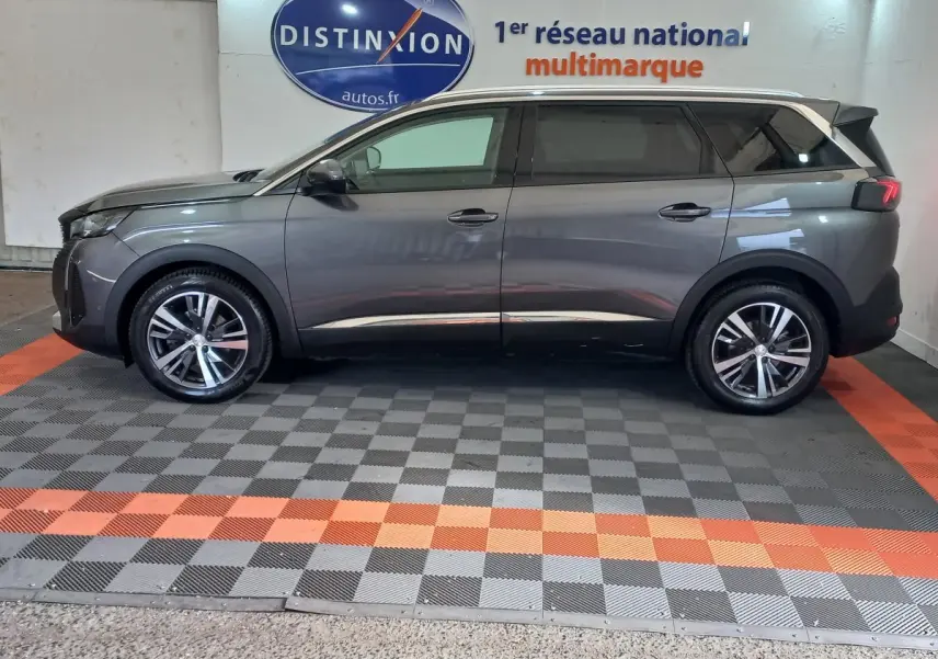 Profil côté gauche d'un Peugeot 5008 gris foncé 2021, finition Allure Pack, dans un showroom multimarque.