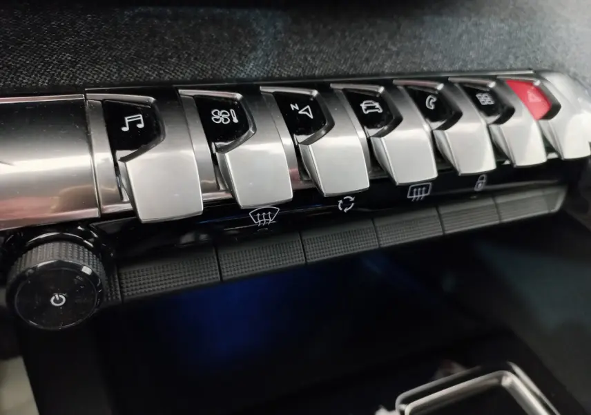 Gros plan sur les commandes chromées du tableau de bord du Peugeot 5008 2021, boutons multifonctions alignés.