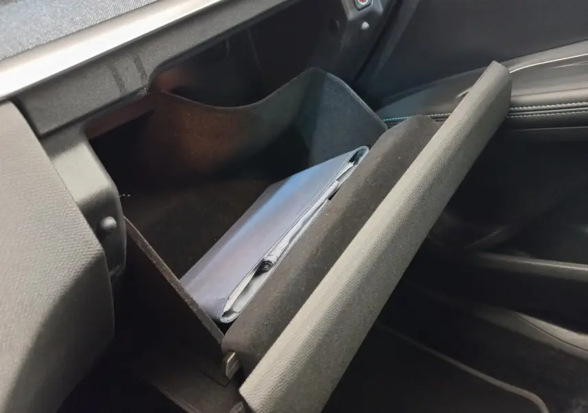 Gant de boîte à gants ouvert côté passager dans Peugeot 5008 gris foncé, intérieur noir avec surpiqûres bleues.