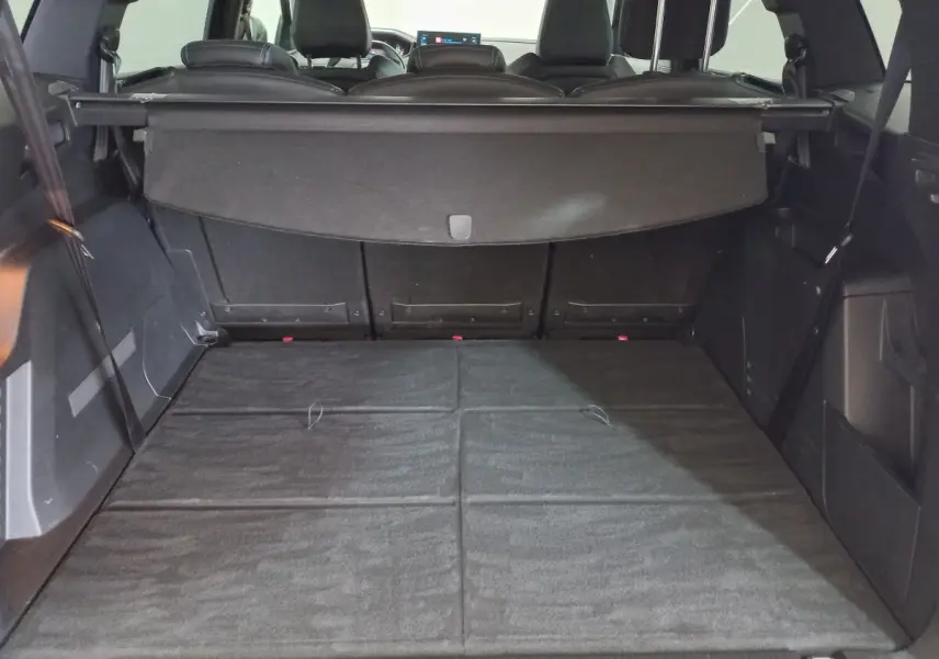 Coffre spacieux du Peugeot 5008 gris foncé vu de l'arrière avec plancher plat et banquettes arrière rabattues.