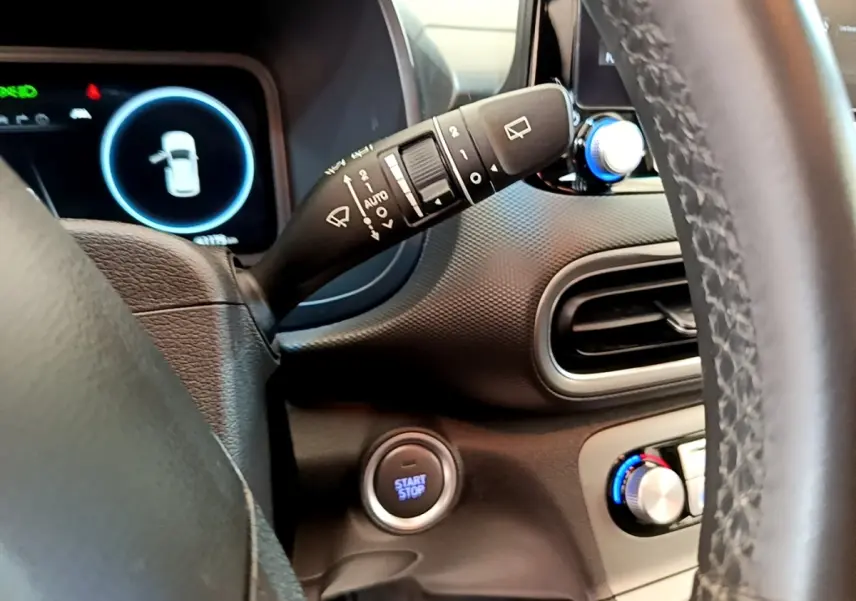 Détail intérieur du tableau de bord du Hyundai Kona électrique 2023, avec bouton start/stop et commandes volant cuir.