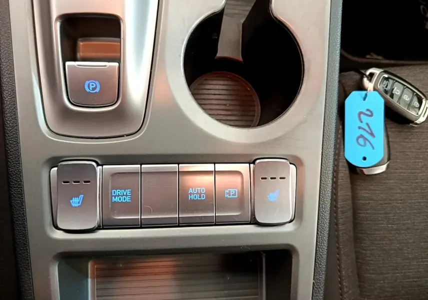 Gros plan sur la console centrale du Hyundai Kona électrique 2023, avec boutons chauffants et mode de conduite.