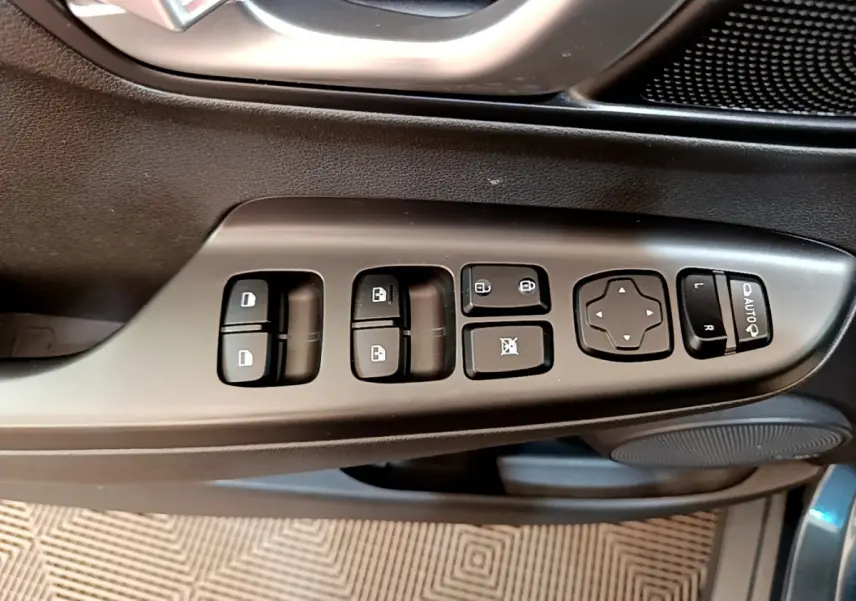 Gros plan sur les commandes de porte côté gauche d’un Hyundai Kona bleu, avec boutons de vitres et réglages des rétroviseurs.