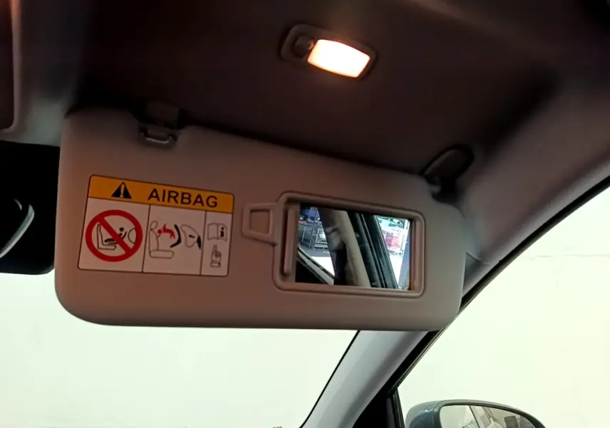 Vue intérieure du pare-soleil côté conducteur avec miroir et avertissement airbag dans un Hyundai Kona bleu 2023.