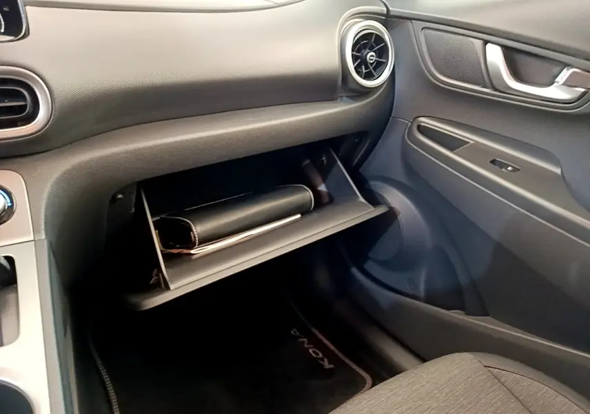Intérieur côté passager du Hyundai Kona électrique 2023, boîte à gants ouverte avec pochette noire visible.
