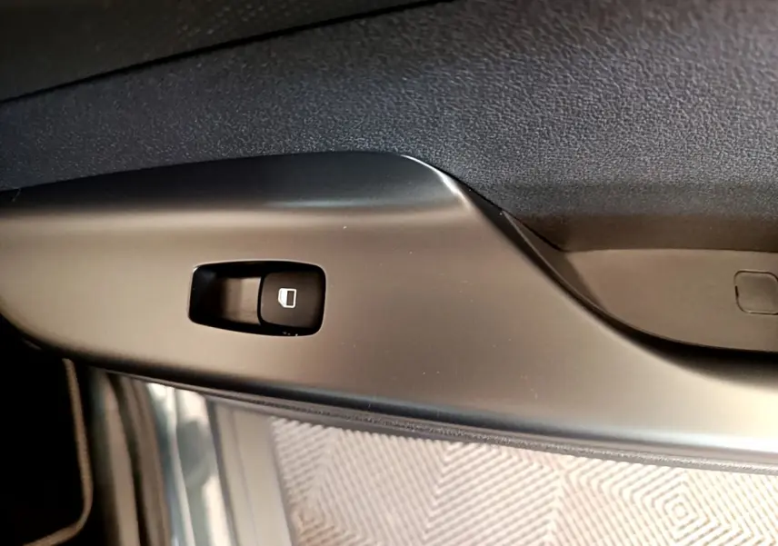 Détail du bouton de commande de la vitre électrique sur la porte intérieure d’une Hyundai Kona bleu électrique.