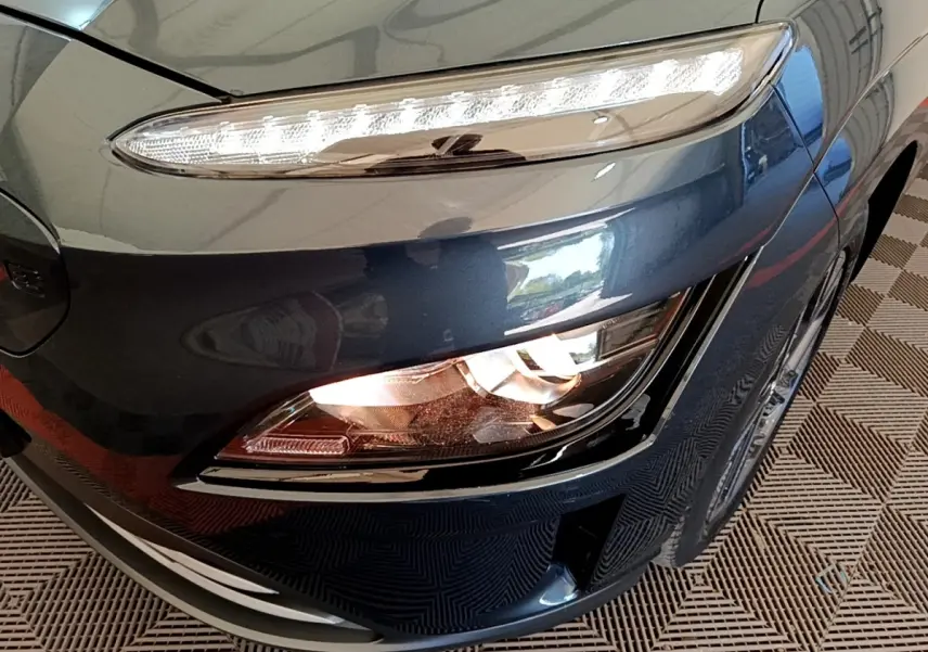 Gros plan sur le phare avant droit bleu électrique d'une Hyundai Kona BEV 64kWh 204ch 2023.