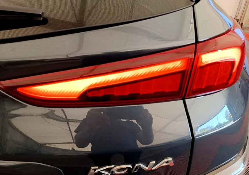 Gros plan sur le feu arrière droit rouge et la carrosserie bleue brillante d’un Hyundai Kona électrique 2023.