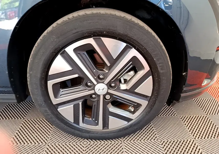 Gros plan sur la roue avant droite d’un Hyundai Kona électrique bleu avec jante alliage bicolore moderne.