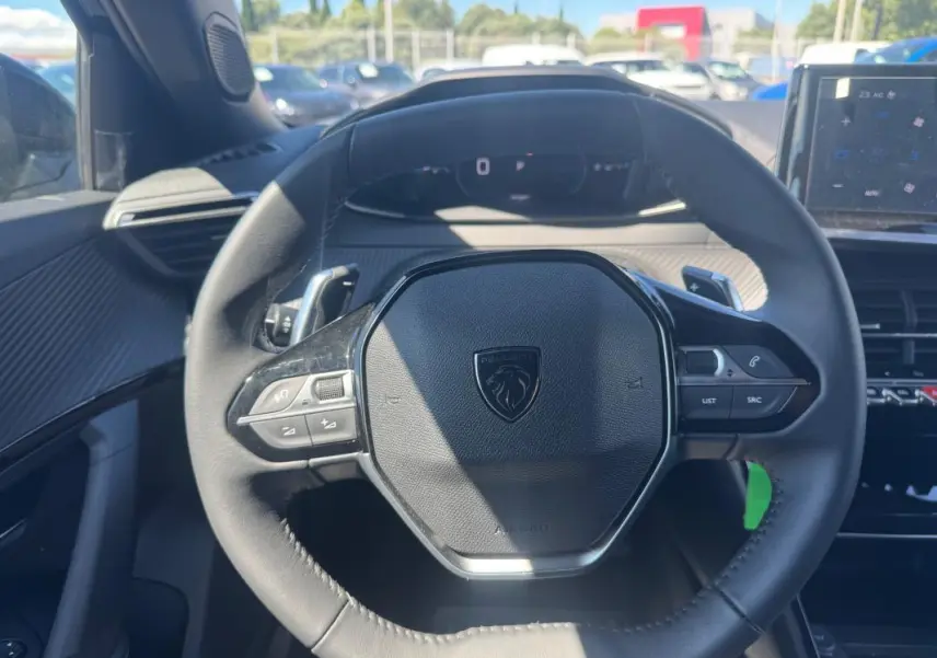 Vue rapprochée du volant noir du Peugeot 2008 Hybrid 136 e-DCS6 Allure 2025 avec commandes intégrées.