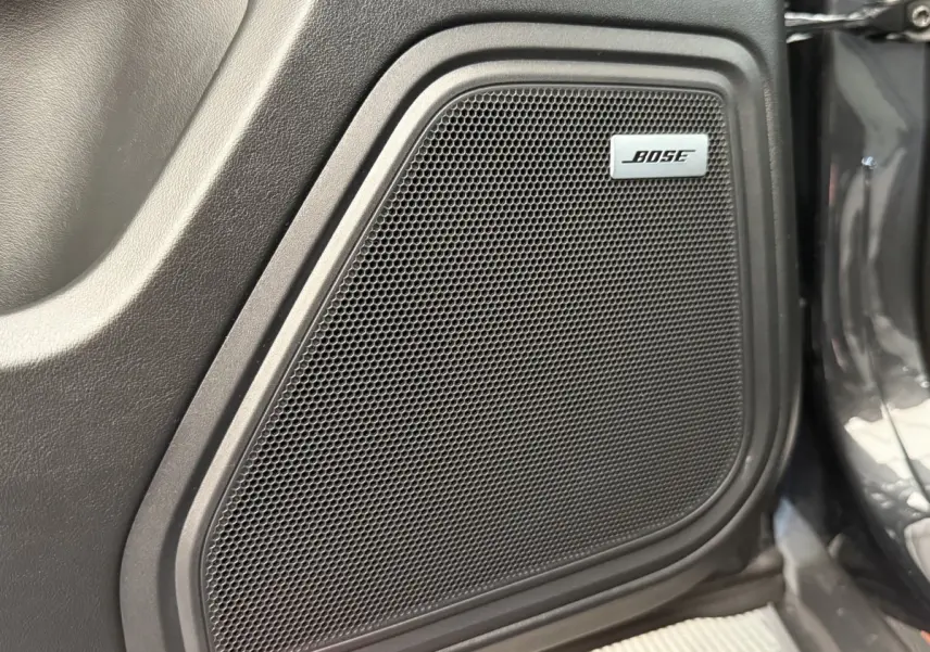 Gros plan sur le haut-parleur Bose intégré dans la porte côté droit d’un Porsche Macan gris foncé.