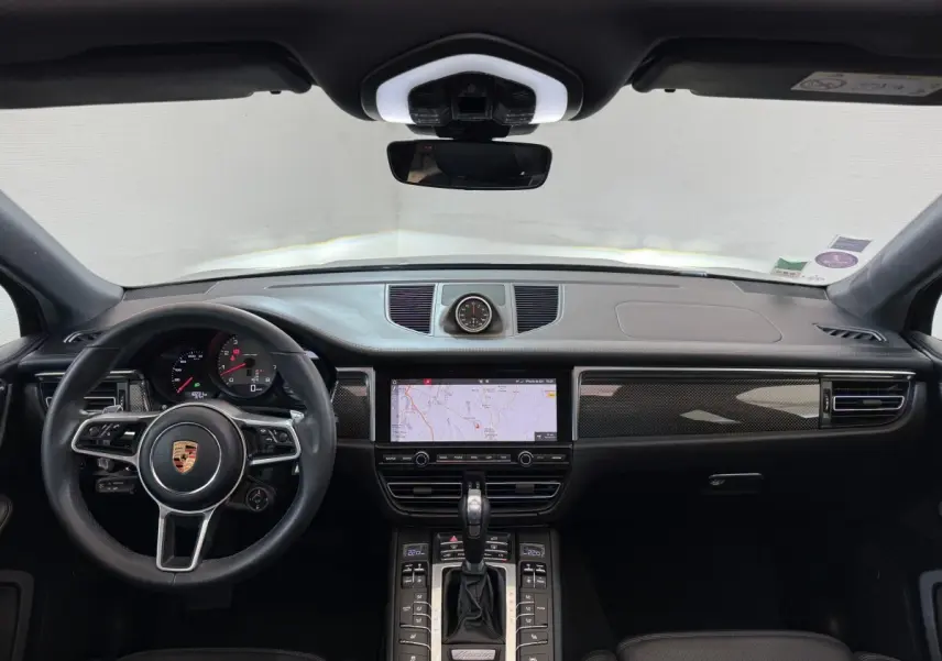 Vue intérieure frontale du tableau de bord noir du Porsche Macan 3.0 S avec volant cuir alu et écran tactile central.
