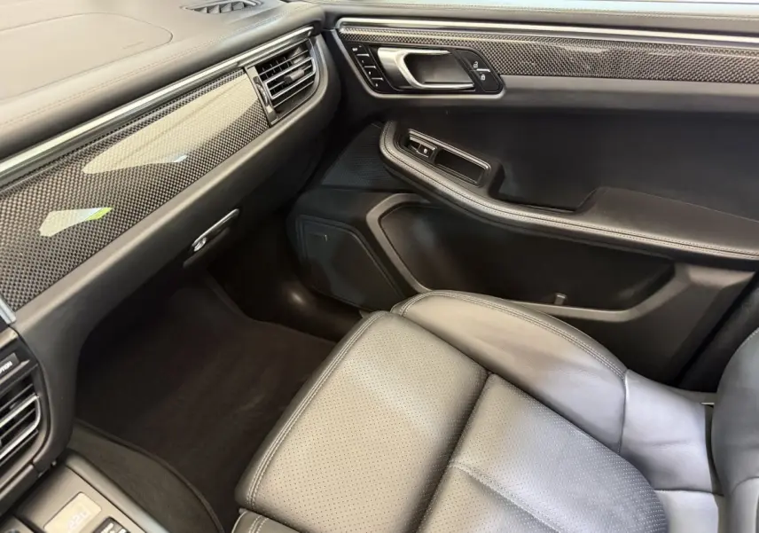 Intérieur côté passager du Porsche Macan 3.0 S 2019, cuir noir et inserts carbone sur tableau de bord et porte.