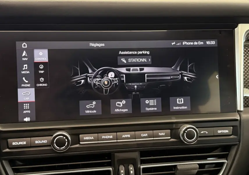 Vue rapprochée de l’écran tactile central du tableau de bord du Porsche Macan 3.0 S gris foncé, affichant les réglages d’assistance parking.