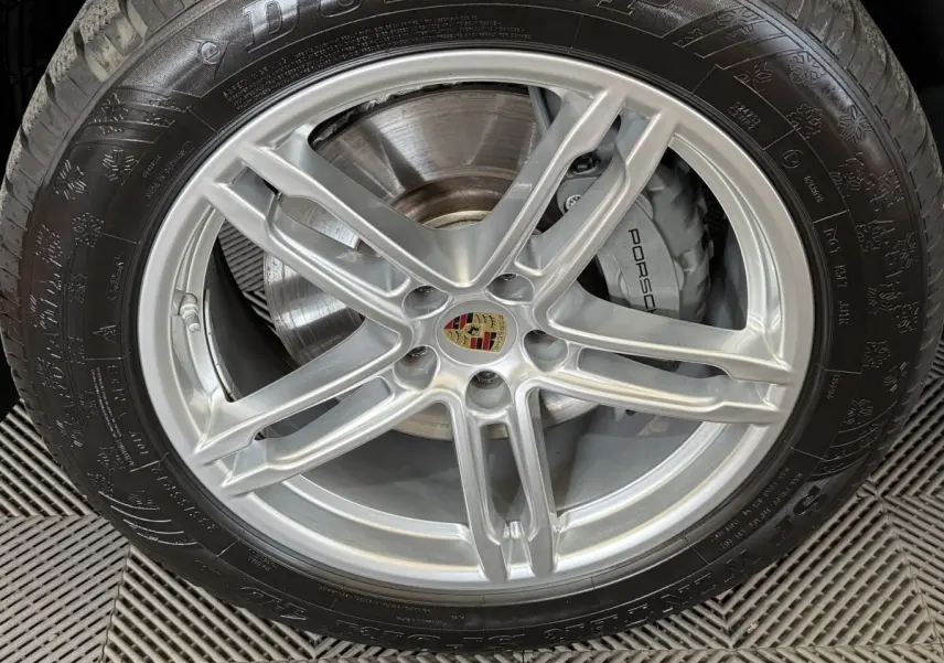 Gros plan sur la jante alu argentée avec logo Porsche et pneu Dunlop du Porsche Macan 3.0 S gris foncé.