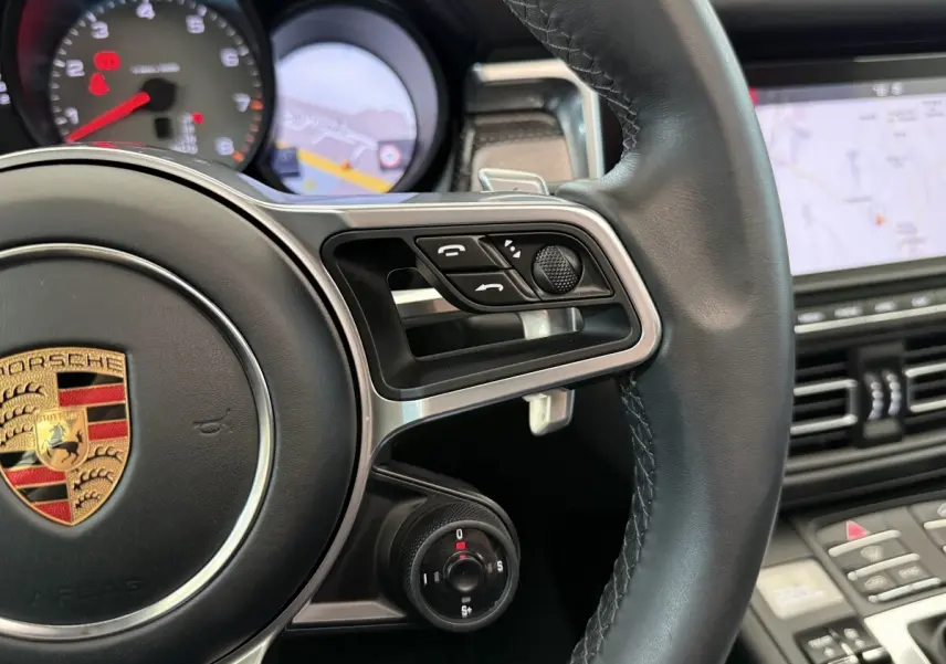 Gros plan sur le volant cuir et alu du Porsche Macan 3.0 S 2019 avec commandes multifonctions et tableau de bord numérique.